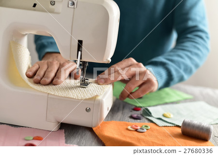 young man using a sewing machine young man using a sewing machine 27680336