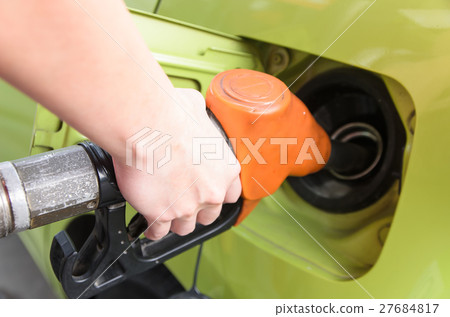 Women hold Fuel nozzle to add fuel at gas station 27684817