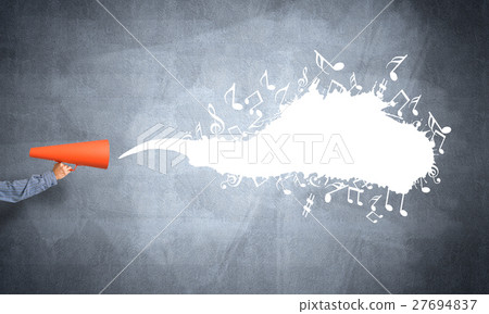 Hand of man holding orange paper trumpet against concrete background Hand of man holding orange paper trumpet against concrete background 27694837
