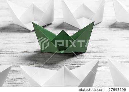 Business leadership concept with white and color paper boats on wooden table Business leadership concept with white and color paper boats on wooden table 27695596