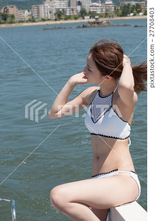A woman blown by a sea breeze in a swimming suit A woman blown by a sea breeze in a swimming suit 27708403