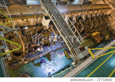 Engineers working on large engine of a ship 27710600