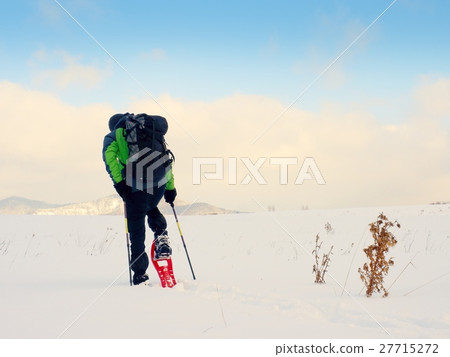 Man with snowshoes walk in snow. Hiker snowshoeing 27715272