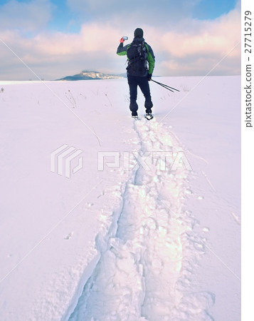 Man with snowshoes take photos by smartphone.  27715279