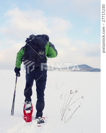 Man with snowshoes walk in snow. Hiker snowshoeing 27715280