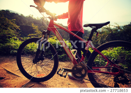 young woman riding mountain bike on forest trail 27718653