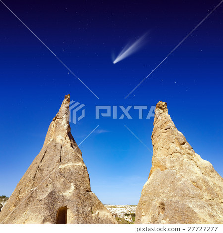 Comet in dark sky with stars, two conical rocks 27727277