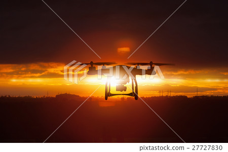 Silhouette of flying drone in glowing sunset sky 27727830