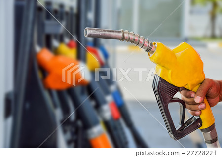 Holding a fuel nozzle against with gas station. 27728221