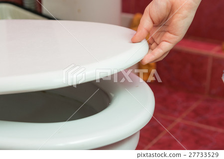 Child's hand puts the toilet seat 27733529