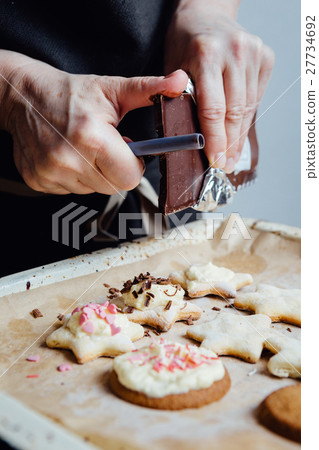 Cook decorating cookies with chocolate 27734692