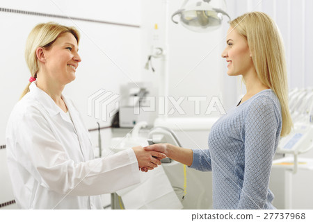 Smiling woman greeting with dental surgeon 27737968