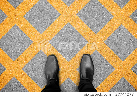 Black shoes standing on no parking zone 27744278