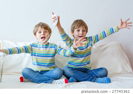 Two little kid boys playing video game at home Two little kid boys playing video game at home 27745361