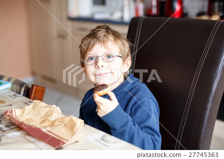 little school boy eating donut indoor in a canteen little school boy eating donut indoor in a canteen 27745363