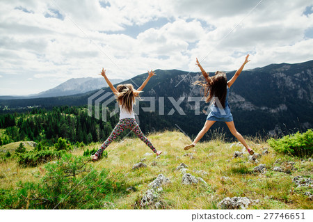 two girls happy jump in mountains 27746651