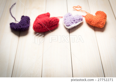 Colorful knitted hearts on light, wooden boards Colorful knitted hearts on light, wooden boards 27752271