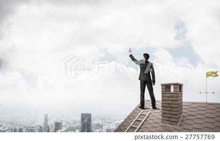 Businessman on house roof touch empty space. Mixed media Businessman on house roof touch empty space. Mixed media 27757769