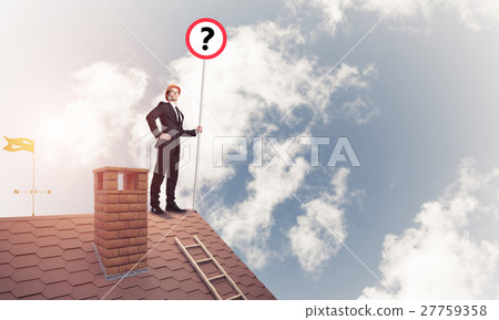 Businessman on brick house roof showing banner with question mar 27759358