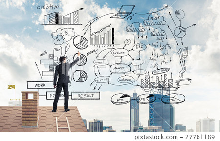 Rear view of businessman on house roof drawing his new business Rear view of businessman on house roof drawing his new business 27761189