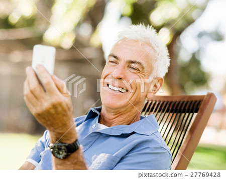 LoMature man outdoors using mobile phone 27769428
