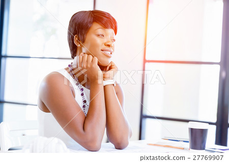 Young woman sitting at a desk in an office and working on blueprint Young woman sitting at a desk in an office and working on blueprint 27769907