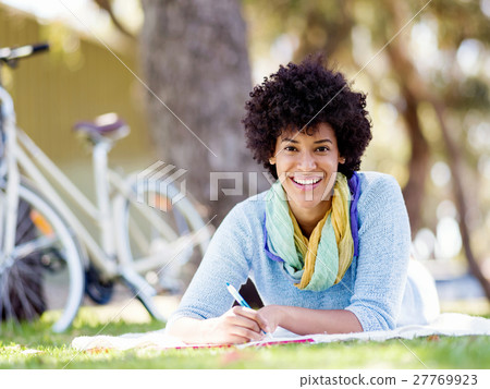 Beautiful young woman writing in her diary outdoors Beautiful young woman writing in her diary outdoors 27769923