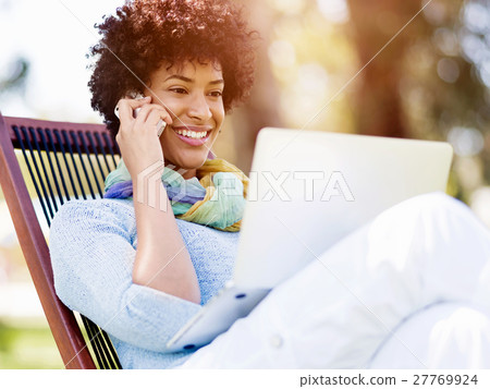 Woman working outdoors in a meadow with laptop Woman working outdoors in a meadow with laptop 27769924