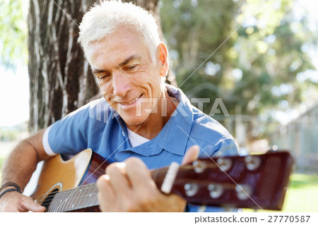 Senior man plying guitar outdoors Senior man plying guitar outdoors 27770587