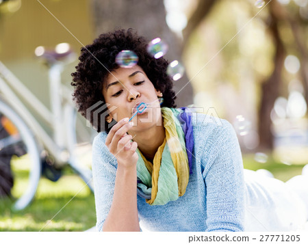 Beautiful woman blowing bubbles in park 27771205