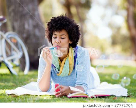 Beautiful woman blowing bubbles in park Beautiful woman blowing bubbles in park 27771704