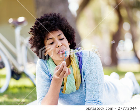 Beautiful woman blowing bubbles in park Beautiful woman blowing bubbles in park 27772044