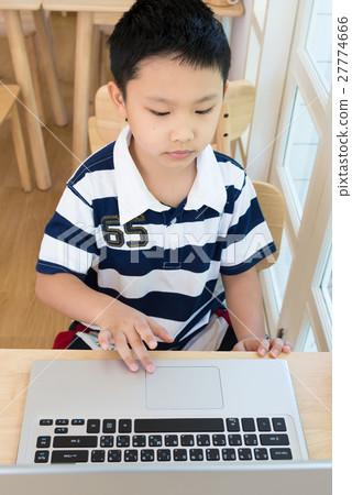 Asian boy sitting at his desk with laptop computer 27774666