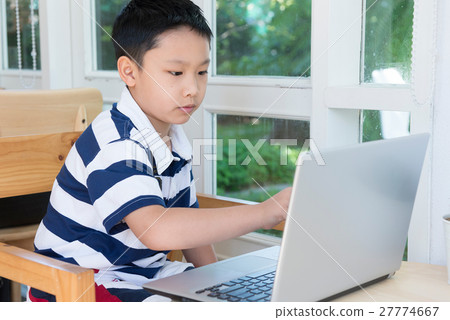 Asian boy sitting at his desk with laptop computer 27774667