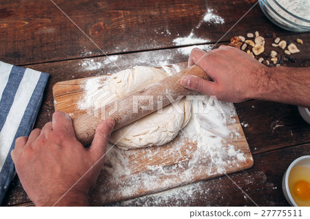 Man rolling dough on cutting board, cook pov 27775511