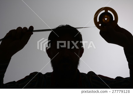 Silhouette of man looking on 8mm film strip 27779128