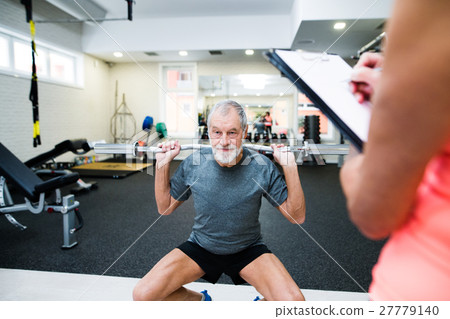 Senior man in gym working out with weights Senior man in gym working out with weights 27779140