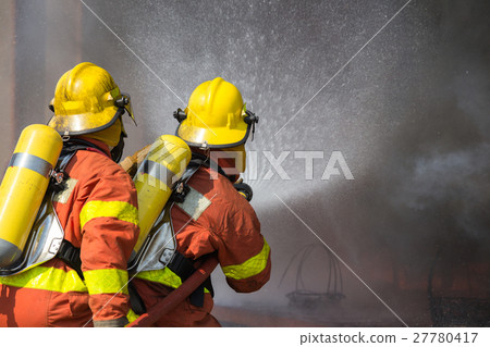 2 firefighters spraying water in fire fighting 2 firefighters spraying water in fire fighting 27780417