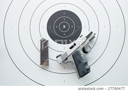 silver .45 pistol with magazine on bullseye target 27780477