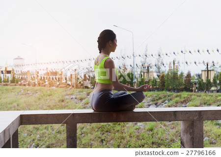 young woman meditates while practicing yoga outdoor in park, relax in nature 27796166