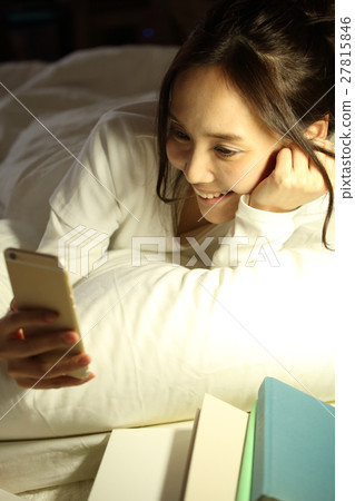 A girl watching a smartphone in a futon 27815846