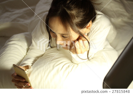 A girl watching a smartphone in a futon 27815848