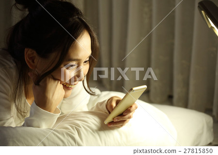 A girl watching a smartphone in a futon 27815850