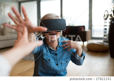 Senior woman wearing virtual reality goggles at Senior woman wearing virtual reality goggles at 27821141