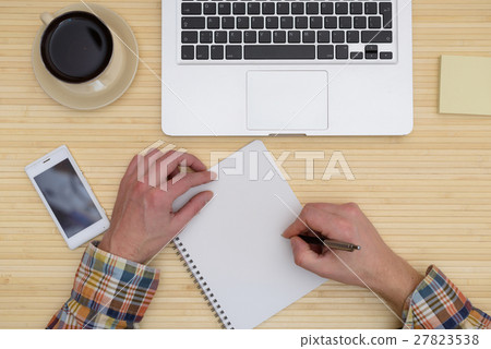 On top of laptop, camera,  Cup hand writes notebo 27823538