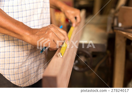 Carpenter hand measuring tape on wood plank 27824017