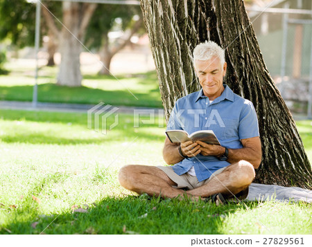 Senior man sittingin park while reading book 27829561