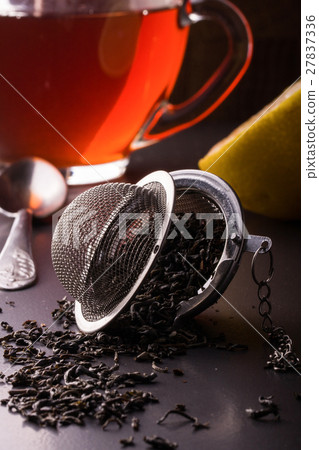 tea strainer with a cup on dark background tea strainer with a cup on dark background 27837336