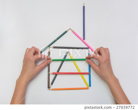Female hands gently put a pencil next to the house layout, close-up Female hands gently put a pencil next to the house layout, close-up 27839772