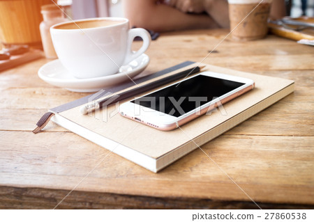 Mobile phone and diary notebook with coffee cup on wood background, selective focus Mobile phone and diary notebook with coffee cup on wood background, selective focus 27860538